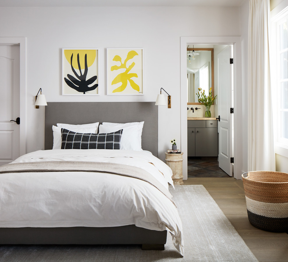 This is an example of a beach style bedroom in San Luis Obispo with white walls and medium hardwood floors.