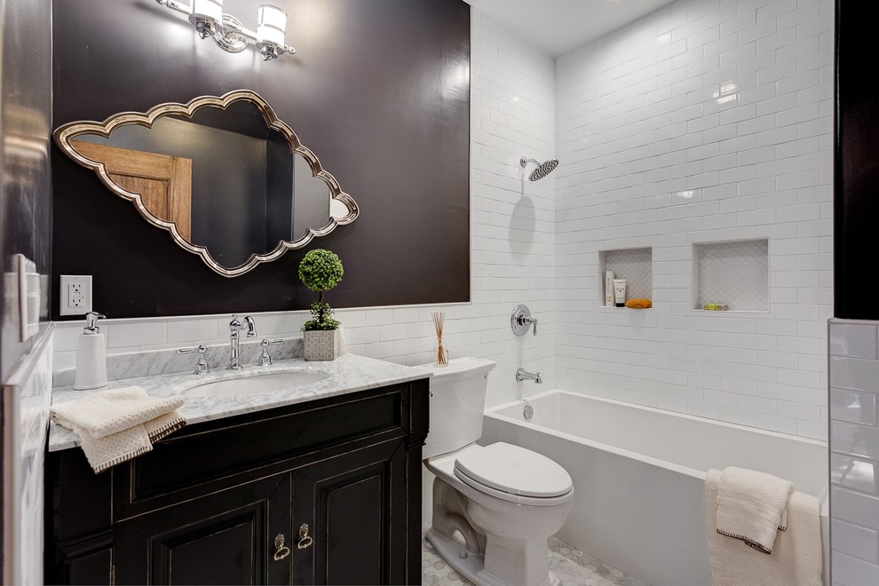 Inspiration for a mid-sized transitional master bathroom in Los Angeles with an undermount sink, recessed-panel cabinets, distressed cabinets, an alcove tub, a shower/bathtub combo, a two-piece toilet, subway tile, white tile, brown walls, pebble tile floors and marble benchtops.