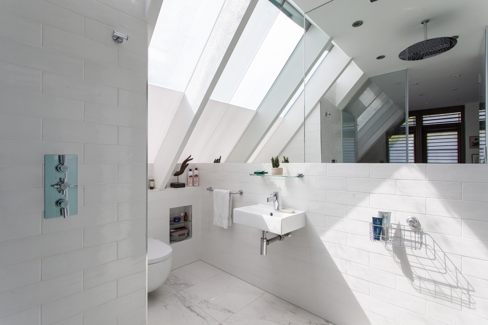 This is an example of a contemporary 3/4 wet room bathroom in London with a wall-mount toilet, white tile, white walls, a wall-mount sink and white floor.
