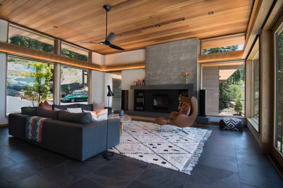 This is an example of a mid-sized midcentury open concept living room in Sacramento with yellow walls, slate floors, a standard fireplace, a concrete fireplace surround, no tv and multi-coloured floor.