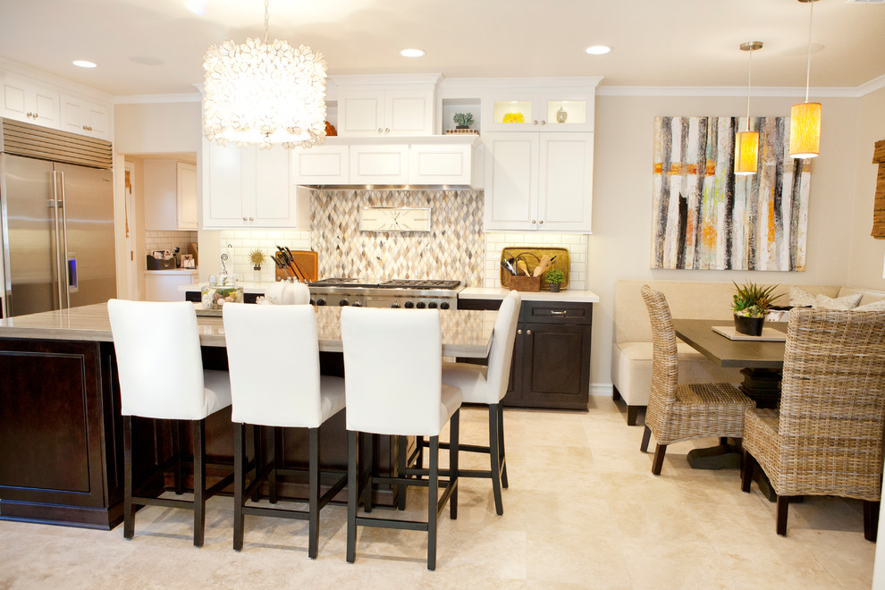 Inspiration for a mid-sized transitional u-shaped limestone floor eat-in kitchen remodel in Orange County with an island, white cabinets, stainless steel appliances, white backsplash and subway tile backsplash