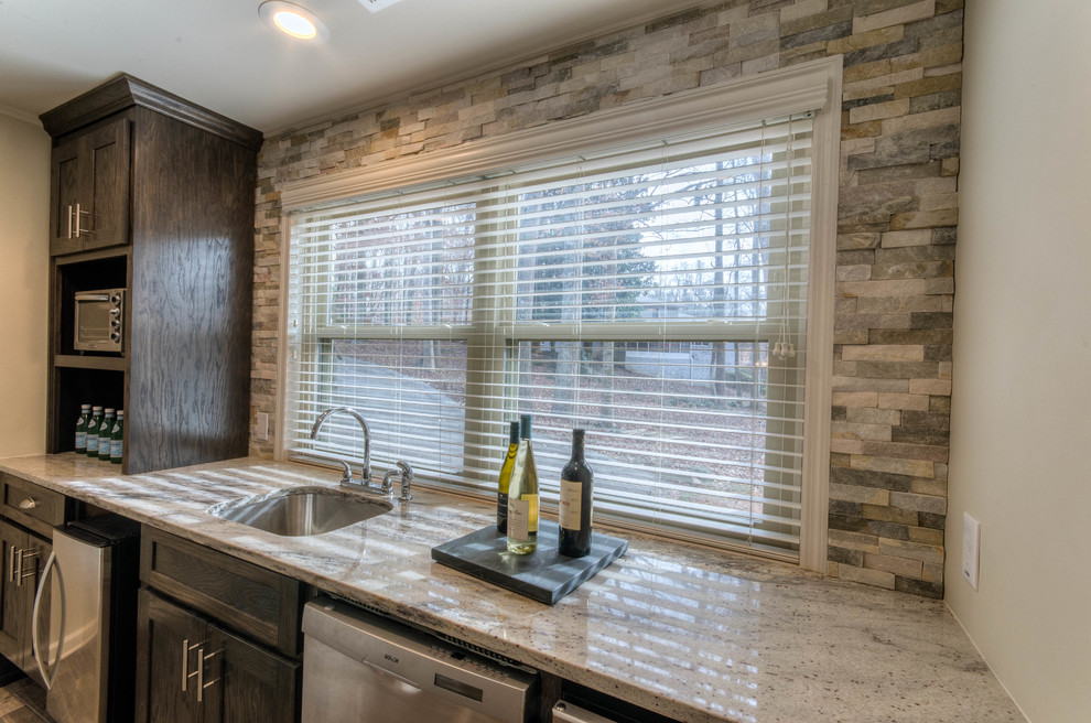 This is an example of a small country single-wall wet bar in Atlanta with an undermount sink, shaker cabinets, dark wood cabinets, granite benchtops, multi-coloured splashback, stone tile splashback and porcelain floors.