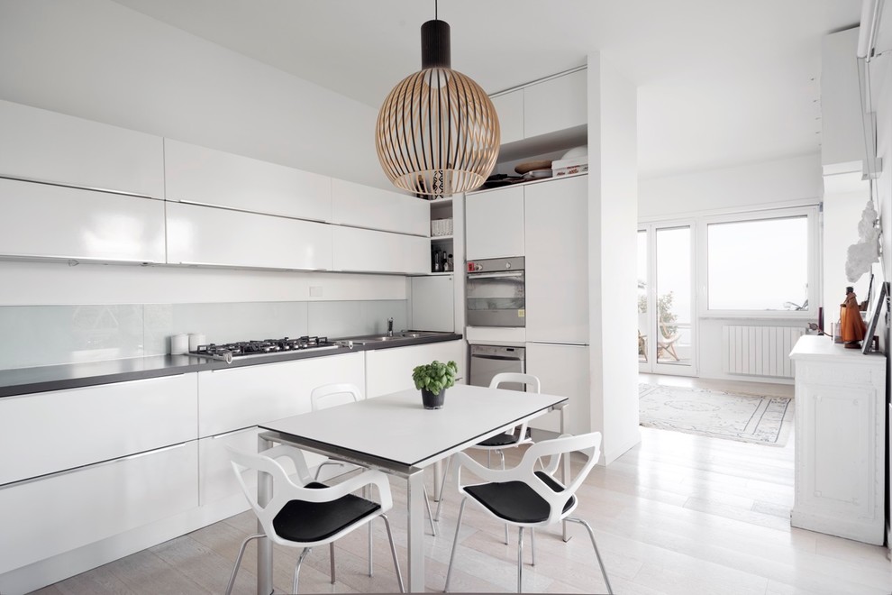 Scandinavian l-shaped kitchen in Milan with flat-panel cabinets, white cabinets and stainless steel appliances.
