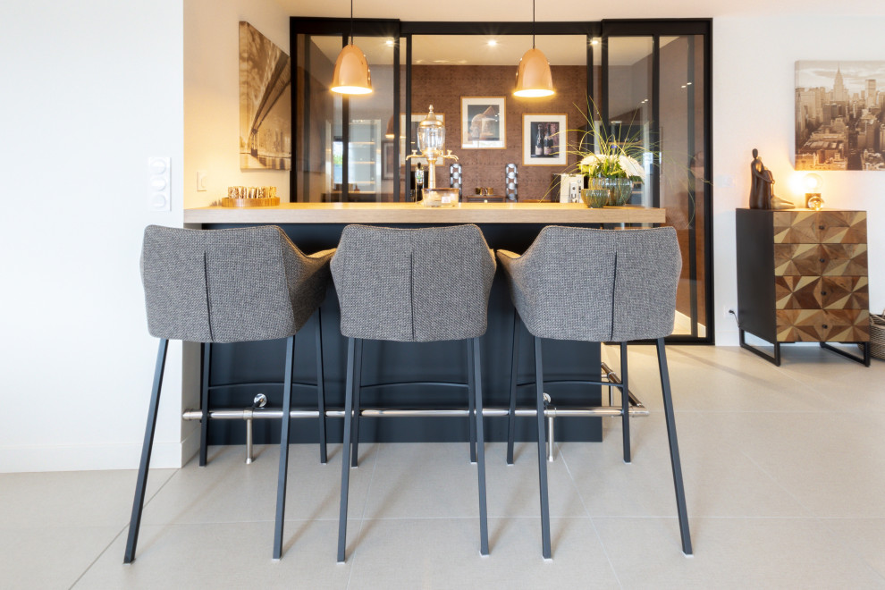 Photo of a large contemporary u-shaped home bar in Other with an integrated sink, flat-panel cabinets, black cabinets, granite worktops, black splashback, ceramic flooring, beige floors and black worktops.