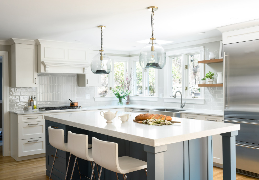 Kitchen - transitional l-shaped light wood floor and beige floor kitchen idea in Boston with white cabinets, subway tile backsplash, an island, a farmhouse sink, shaker cabinets, gray backsplash, stainless steel appliances and gray countertops