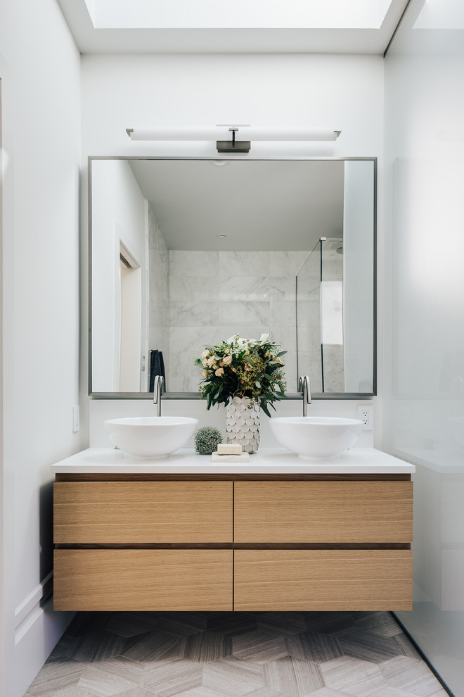 This is an example of a mid-sized contemporary 3/4 bathroom in San Francisco with white walls, a vessel sink, soapstone benchtops, flat-panel cabinets, light wood cabinets, grey floor, a freestanding tub, an open shower, a two-piece toilet, ceramic floors, a hinged shower door, white benchtops, a double vanity and a freestanding vanity.