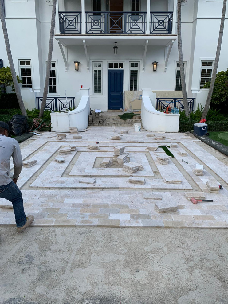 This is an example of a large contemporary front patio in Miami with natural stone paving.