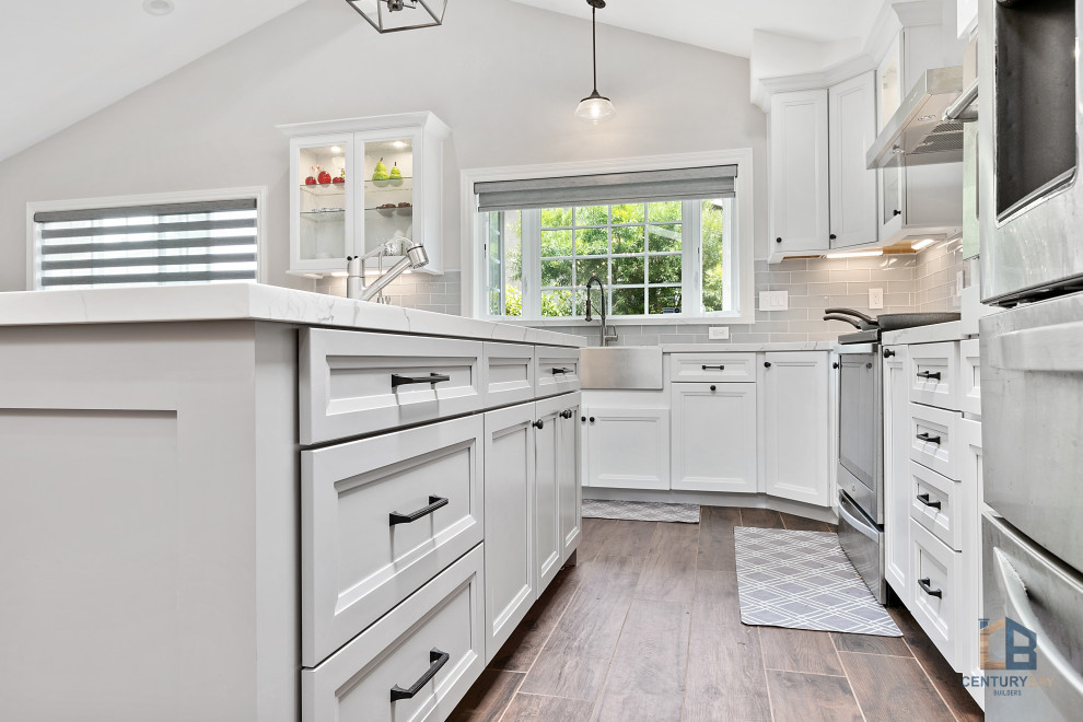 Elegant l-shaped porcelain tile and multicolored floor eat-in kitchen photo in San Francisco with an undermount sink, raised-panel cabinets, white cabinets, quartz countertops, gray backsplash, porcelain backsplash, stainless steel appliances, an island and white countertops