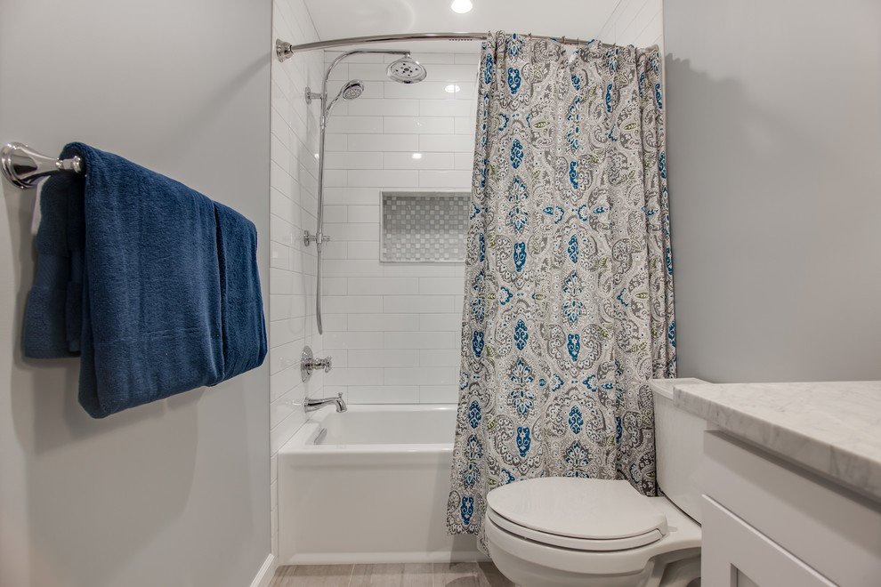 Mid-sized transitional kids bathroom in Philadelphia with shaker cabinets, white cabinets, an alcove tub, a two-piece toilet, white tile, ceramic tile, grey walls, ceramic floors, an undermount sink and marble benchtops.