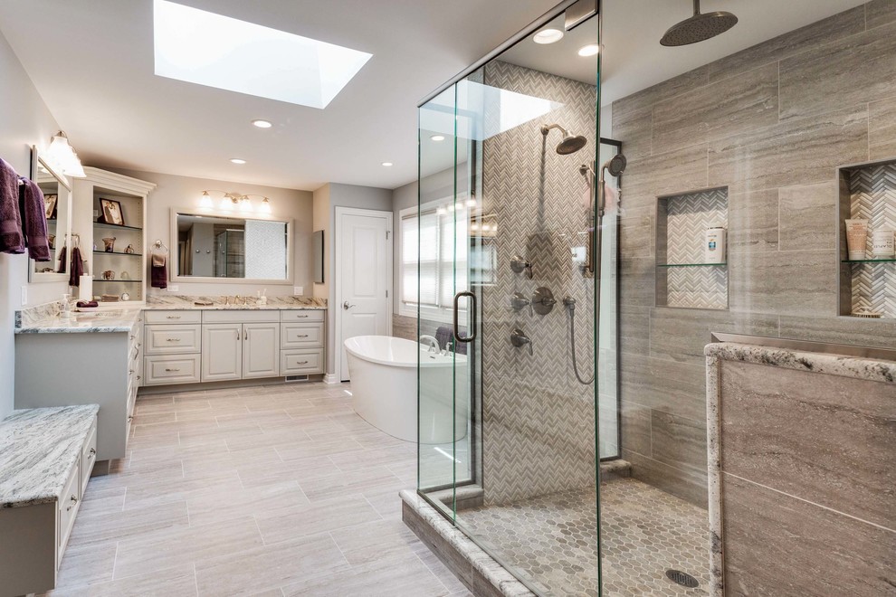 Large transitional master brown tile, beige tile and porcelain tile porcelain tile and beige floor freestanding bathtub photo in Chicago with raised-panel cabinets, white cabinets, beige walls, an undermount sink, granite countertops, a hinged shower door and beige countertops