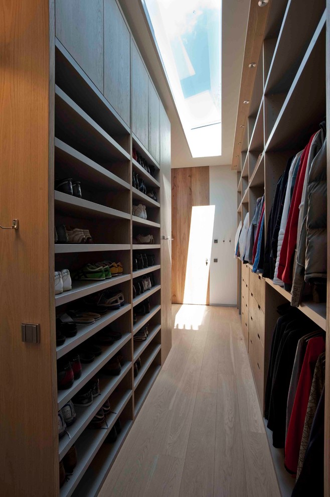 Design ideas for a large contemporary gender-neutral walk-in wardrobe in New York with flat-panel cabinets, medium wood cabinets and light hardwood floors.