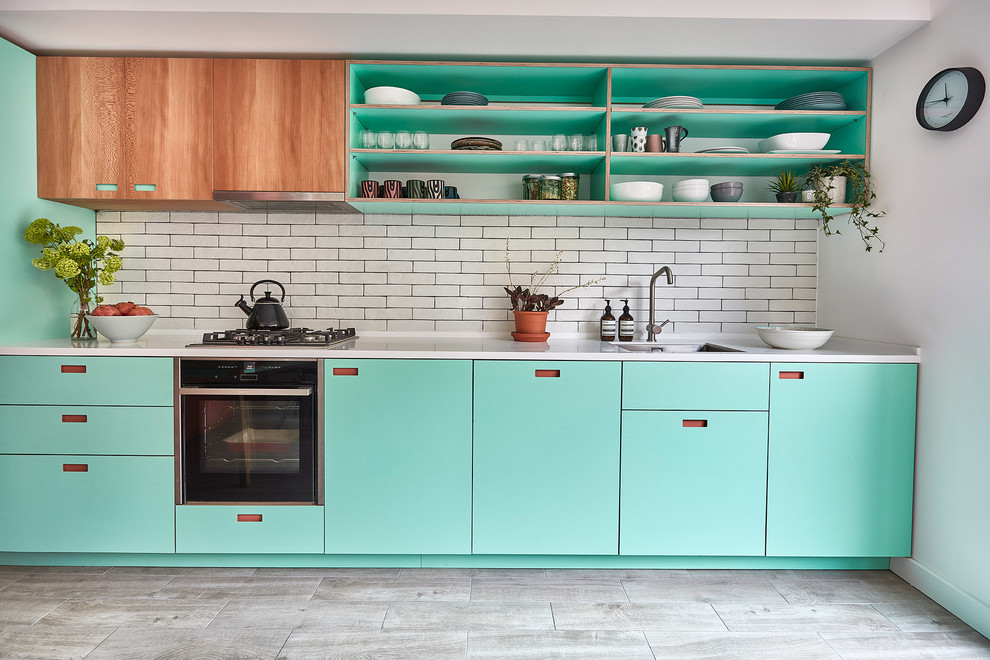 Photo of a mid-sized scandinavian kitchen in London with an undermount sink, turquoise cabinets, solid surface benchtops, white splashback, subway tile splashback, porcelain floors, no island, grey floor, white benchtop and open cabinets.