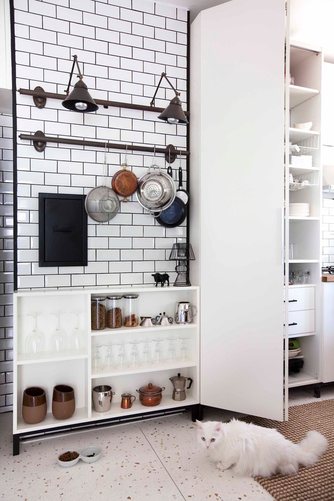 Photo of an industrial kitchen in Other with flat-panel cabinets, white splashback and subway tile splashback.