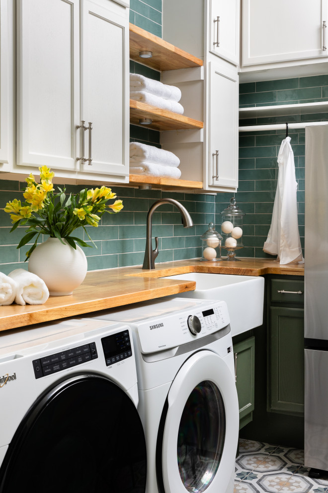 Inspiration for a small traditional laundry room in Dallas with a farmhouse sink, shaker cabinets, green cabinets, wood benchtops, green splashback, porcelain splashback, porcelain floors, a side-by-side washer and dryer and green floor.