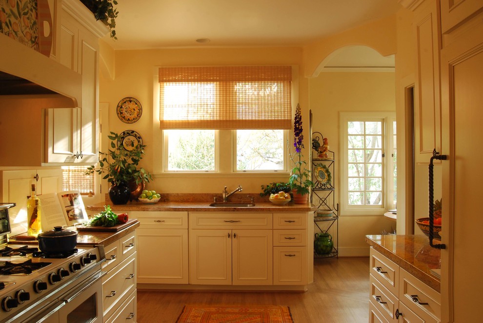 Mid-sized mediterranean single-wall kitchen pantry in San Francisco with a single-bowl sink, raised-panel cabinets, yellow cabinets, granite benchtops, yellow splashback, coloured appliances, light hardwood floors and no island.