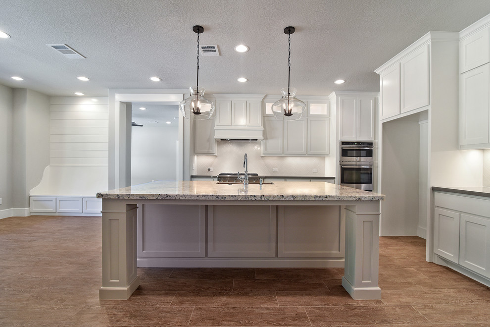 Inspiration for a large transitional eat-in kitchen in Houston with a farmhouse sink, shaker cabinets, white cabinets, granite benchtops, white splashback, subway tile splashback, stainless steel appliances, porcelain floors and with island.