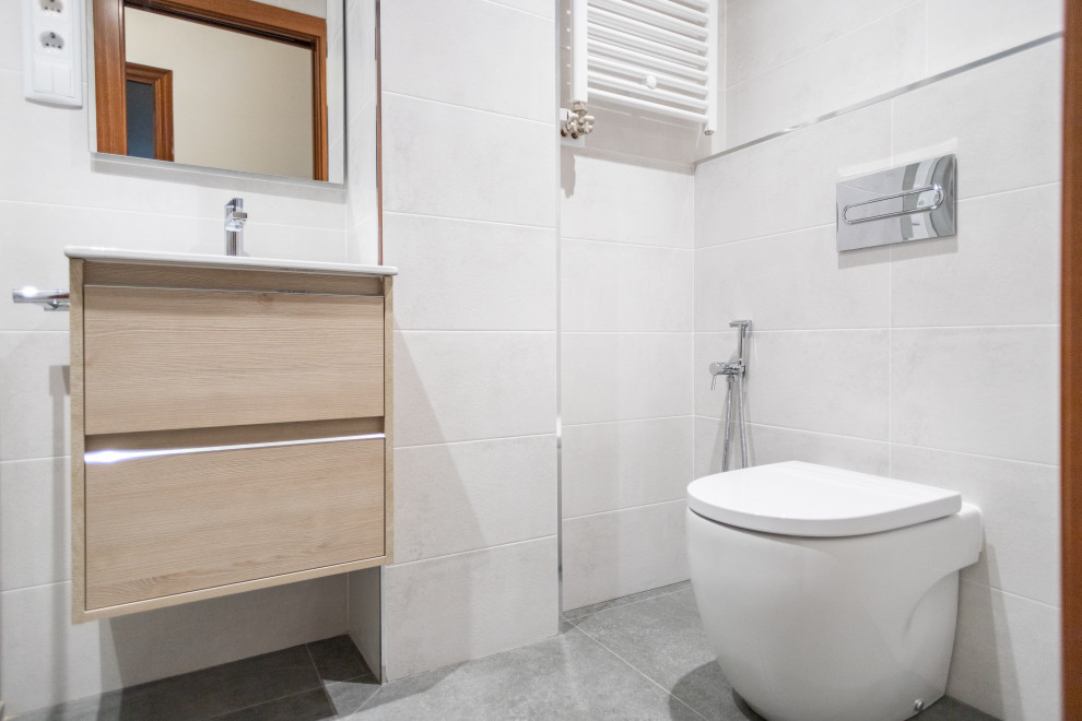 This is an example of a medium sized mediterranean ensuite bathroom in Barcelona with flat-panel cabinets, medium wood cabinets, a built-in shower, a one-piece toilet, grey tiles, ceramic tiles, ceramic flooring, a trough sink, grey floors, a sliding door, white worktops, an enclosed toilet, a single sink and a floating vanity unit.