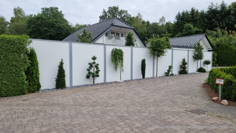 This is an example of a medium sized contemporary side formal and private full sun garden for summer in Other with concrete paving and a stone fence.