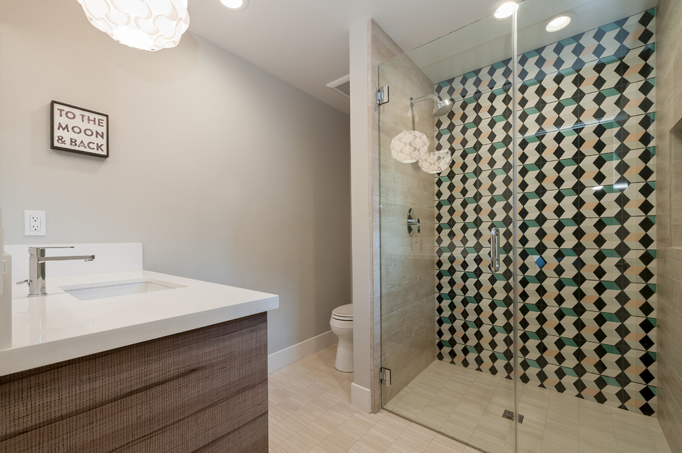 This is an example of a mid-sized contemporary master bathroom in San Diego with an undermount sink, flat-panel cabinets, dark wood cabinets, a curbless shower, multi-coloured tile, grey walls, a one-piece toilet, porcelain tile, mosaic tile floors, engineered quartz benchtops, beige floor and a hinged shower door.