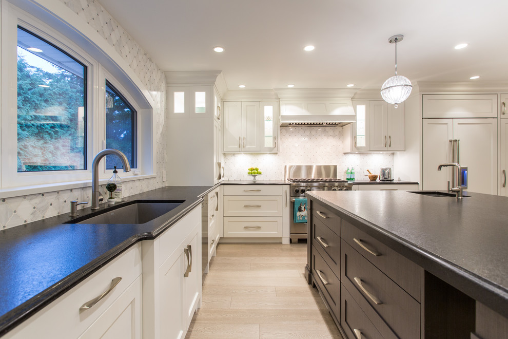 Large transitional l-shaped medium tone wood floor and beige floor eat-in kitchen photo in Vancouver with an undermount sink, shaker cabinets, white cabinets, granite countertops, gray backsplash, marble backsplash, stainless steel appliances, an island and black countertops