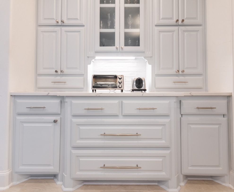 Exempel på ett stort klassiskt vit vitt kök, med en undermonterad diskho, luckor med upphöjd panel, grå skåp, bänkskiva i kvarts, vitt stänkskydd, stänkskydd i glaskakel, rostfria vitvaror, klinkergolv i porslin, en köksö och beiget golv