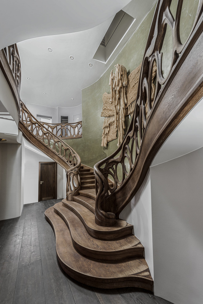 This is an example of an expansive eclectic painted wood curved staircase in Berlin with painted wood risers and wood railing.