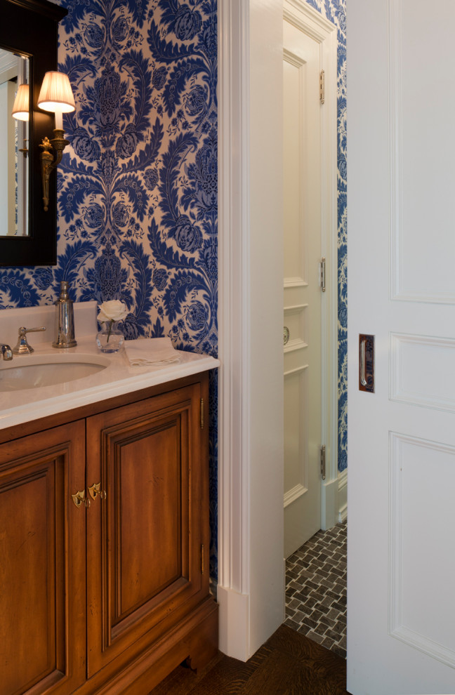 Réalisation d'un WC et toilettes tradition en bois brun avec un placard à porte affleurante, un mur bleu, parquet foncé, un lavabo encastré, un sol marron, un plan de toilette beige, meuble-lavabo sur pied et du papier peint.