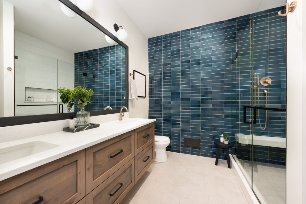 Photo of a small transitional master bathroom in Chicago with recessed-panel cabinets, medium wood cabinets, an alcove shower, a one-piece toilet, blue tile, ceramic tile, white walls, mosaic tile floors, a drop-in sink, engineered quartz benchtops, beige floor, a hinged shower door, white benchtops, a double vanity and a floating vanity.