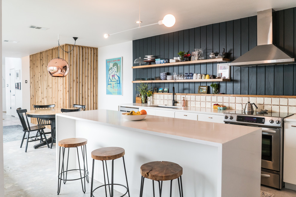 Contemporary single-wall eat-in kitchen in Austin with an undermount sink, flat-panel cabinets, white cabinets, white splashback, stainless steel appliances, with island, white floor and concrete floors.
