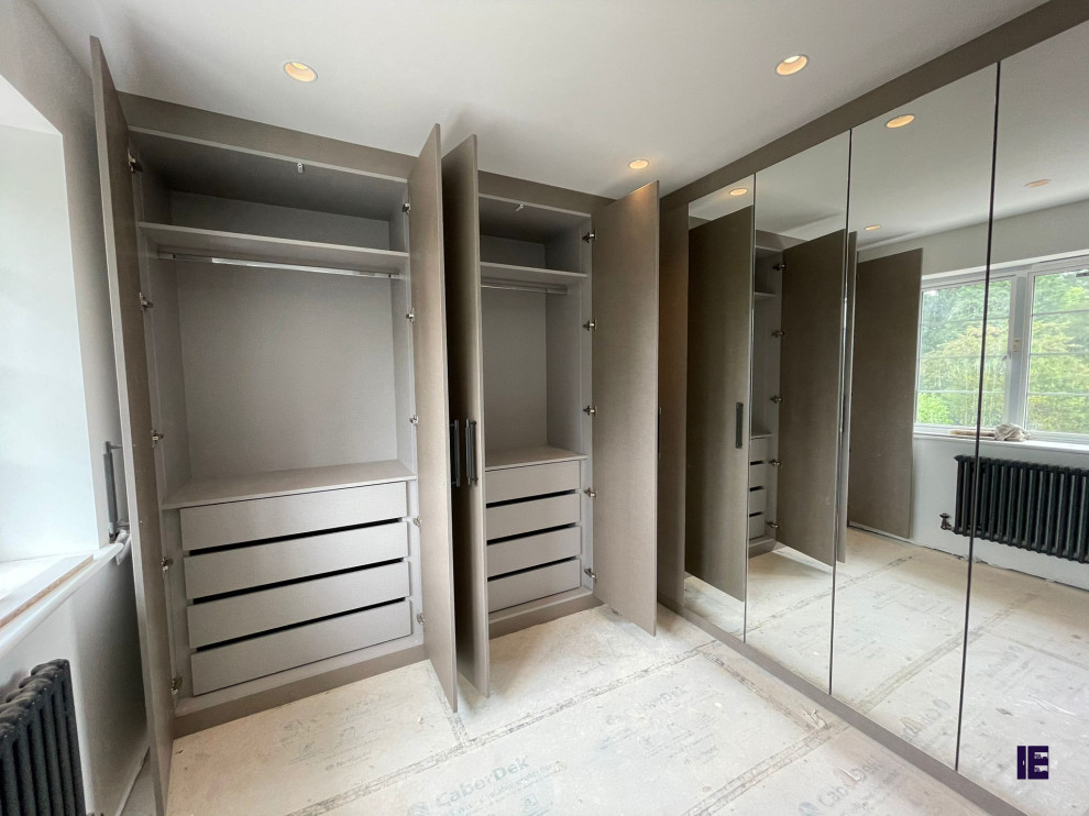 Aménagement d'une petite armoire encastrée moderne avec un placard avec porte à panneau surélevé, des portes de placard grises et un sol blanc.