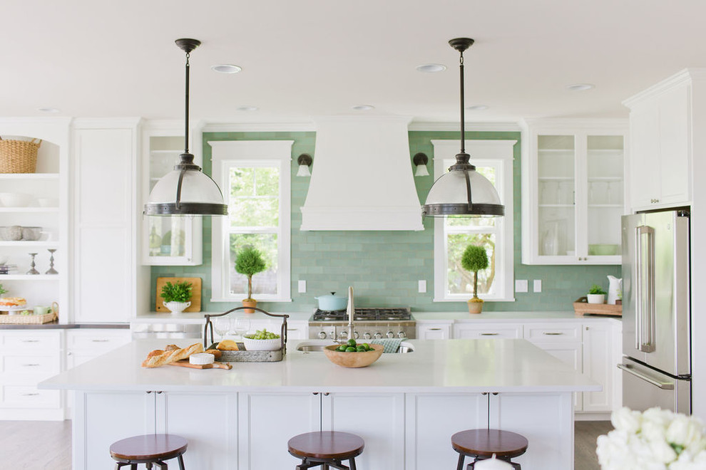Design ideas for a large mediterranean l-shaped open plan kitchen in Minneapolis with beaded inset cabinets, white cabinets, marble benchtops, green splashback, ceramic splashback, stainless steel appliances, dark hardwood floors, with island, brown floor and white benchtop.