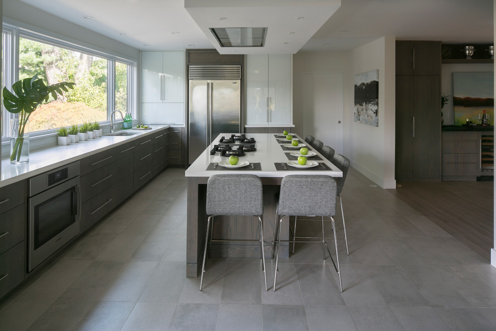 This is an example of a large contemporary l-shaped kitchen in New York with an undermount sink, flat-panel cabinets, medium wood cabinets, quartz benchtops, white splashback, glass tile splashback, stainless steel appliances, porcelain floors and with island.