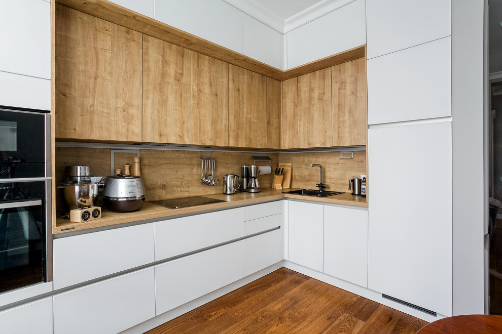 This is an example of a large scandinavian l-shaped eat-in kitchen in Other with a single-bowl sink, glass-front cabinets, white cabinets, laminate benchtops, brown splashback, black appliances, painted wood floors, no island, brown floor and brown benchtop.