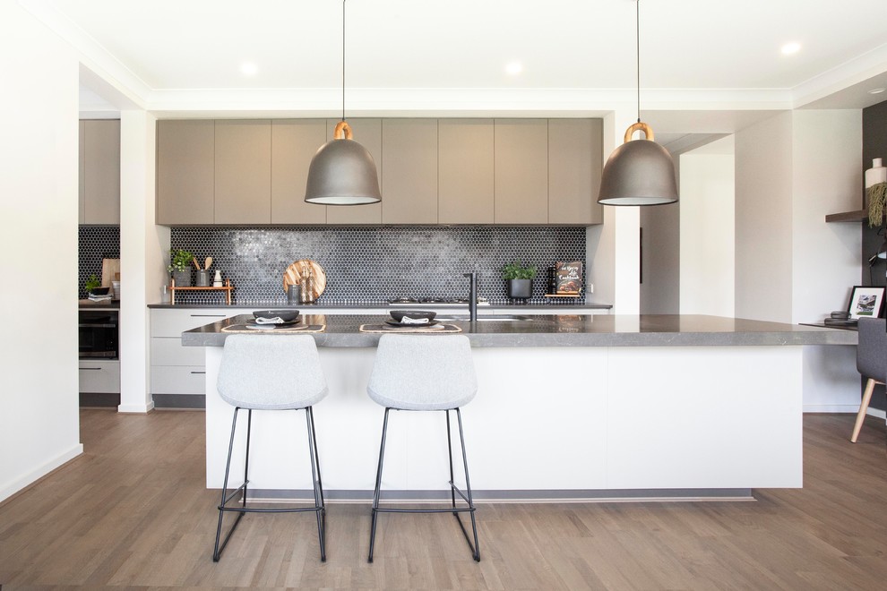 Design ideas for a contemporary galley kitchen in Melbourne with an undermount sink, flat-panel cabinets, grey cabinets, black splashback, mosaic tile splashback, medium hardwood floors, with island, brown floor and grey benchtop.