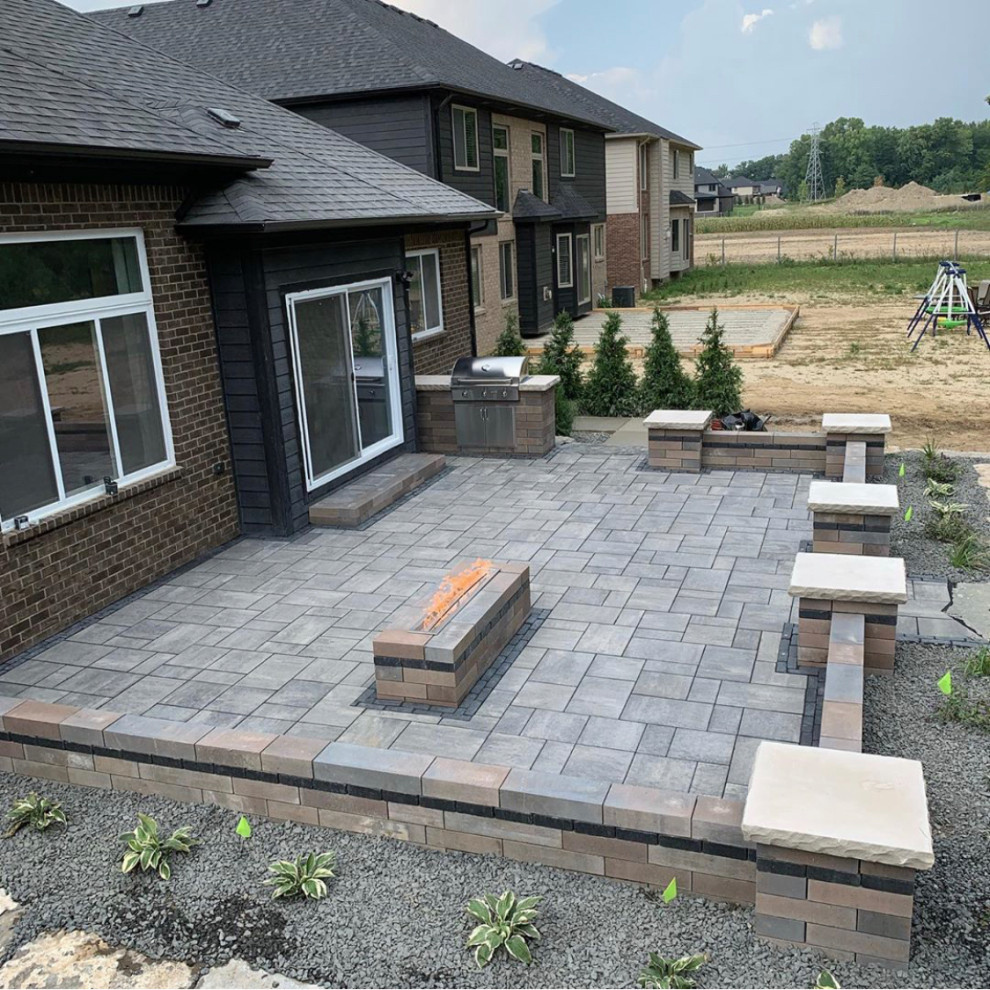 Large transitional backyard patio in Detroit with a fire feature, natural stone pavers and no cover.
