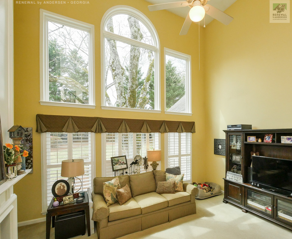 Inspiration for a large enclosed living room in Atlanta with yellow walls, carpet, a standard fireplace, a wood fireplace surround, a freestanding tv, beige floor and vaulted.