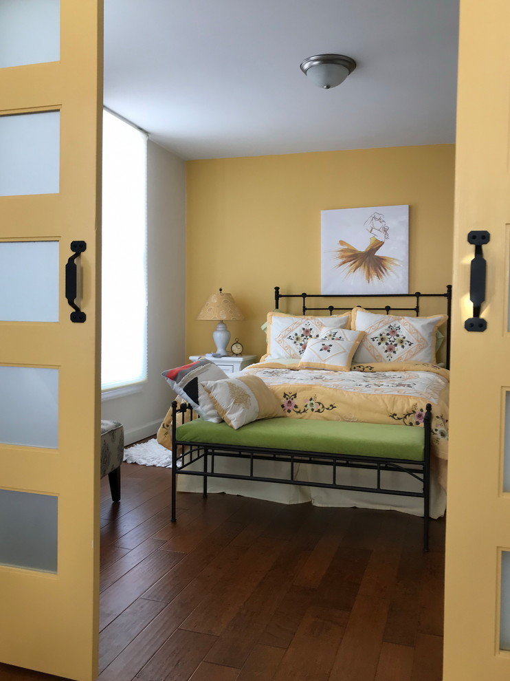 This is an example of a mid-sized transitional guest bedroom in Indianapolis with yellow walls, medium hardwood floors, no fireplace and brown floor.