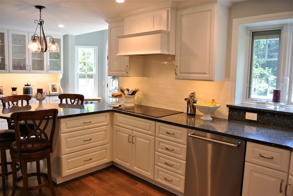Example of a transitional light wood floor eat-in kitchen design in Boston with an undermount sink, raised-panel cabinets, white cabinets, granite countertops, white backsplash, subway tile backsplash and stainless steel appliances