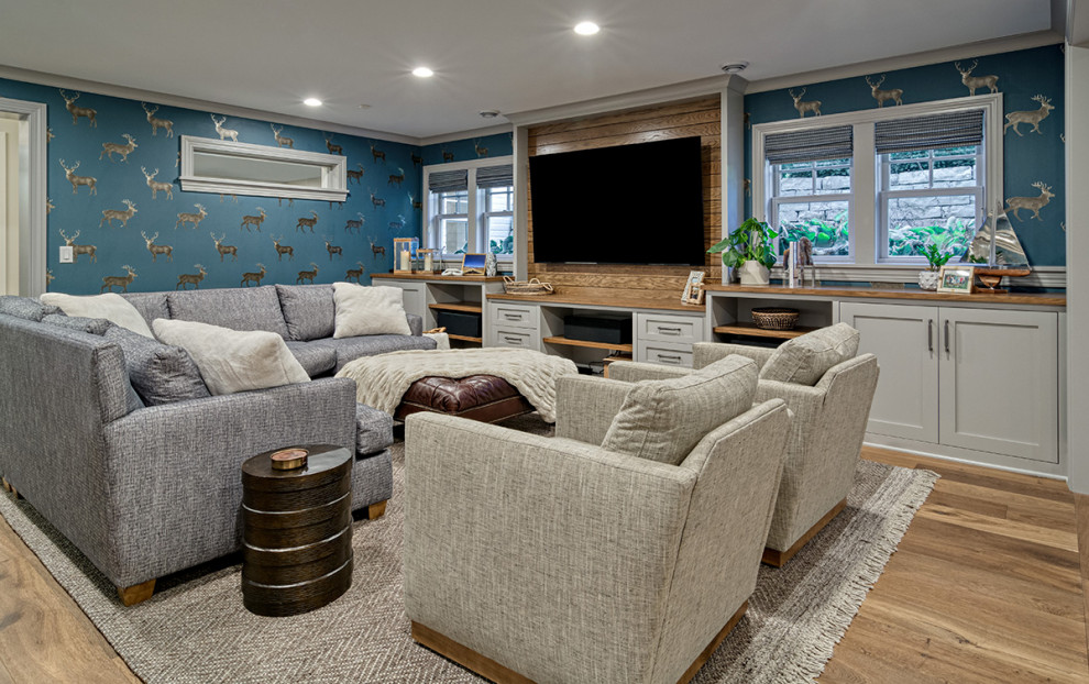 Cette photo montre une grande salle de séjour chic ouverte avec un bar de salon, un mur gris, sol en stratifié, un téléviseur fixé au mur, un sol marron et du papier peint.
