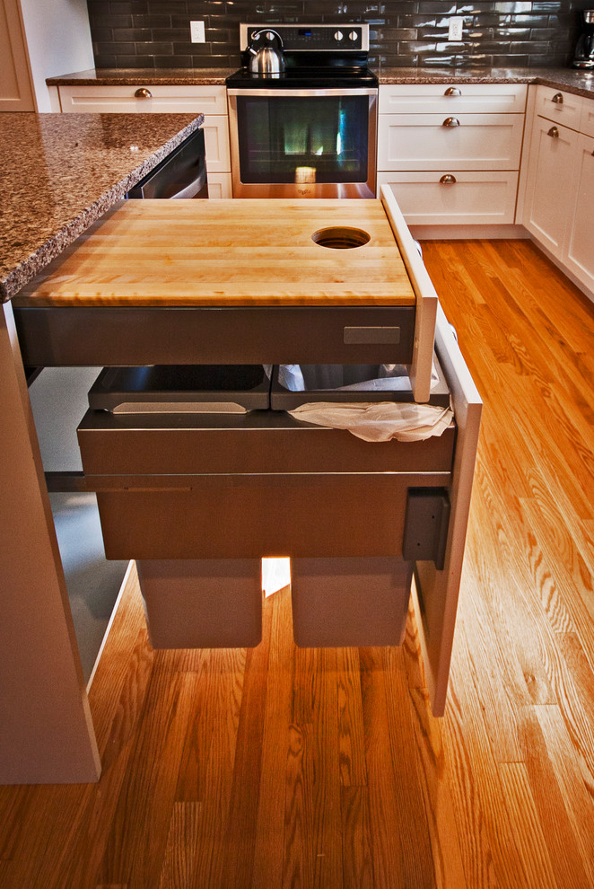 Mid-sized transitional l-shaped light wood floor eat-in kitchen photo with a double-bowl sink, white cabinets, quartz countertops, brown backsplash, ceramic backsplash, stainless steel appliances, an island and shaker cabinets