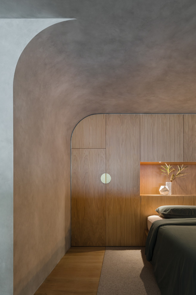 Small modern bedroom in Sydney with grey walls, light hardwood floors and brown floor.