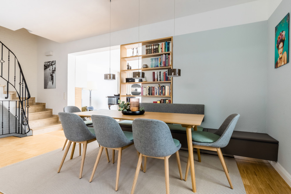 Inspiration for a large scandinavian dining room in Dusseldorf with grey walls, bamboo floors, a hanging fireplace, a metal fireplace surround, brown floor, wallpaper and wallpaper.