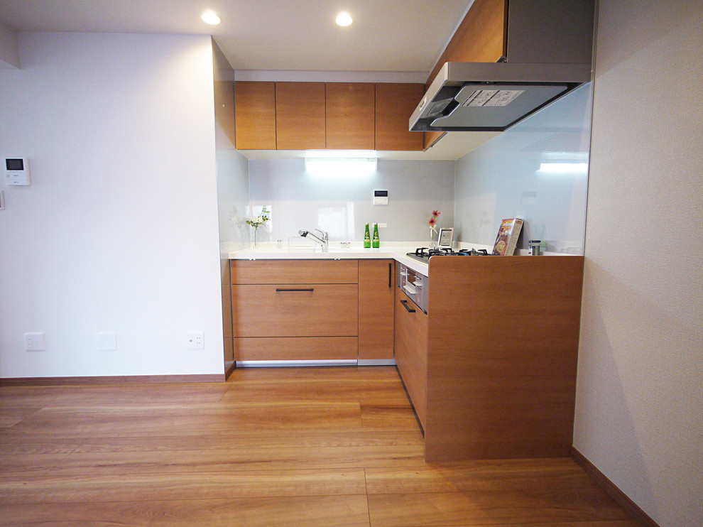 Design ideas for a country l-shaped eat-in kitchen in Tokyo with medium wood cabinets, white splashback and medium hardwood floors.