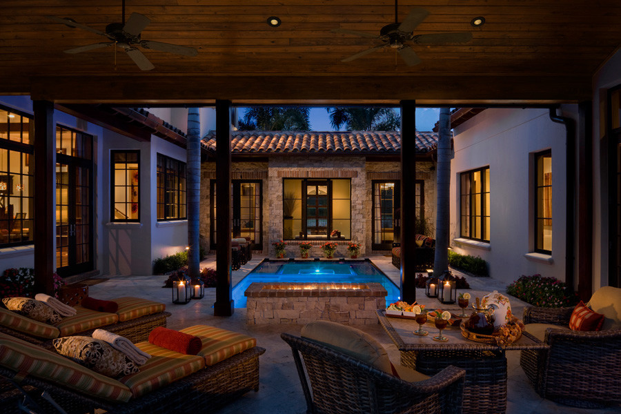 Inspiration for a mid-sized mediterranean courtyard patio in Orlando with a fire feature, concrete pavers and a roof extension.