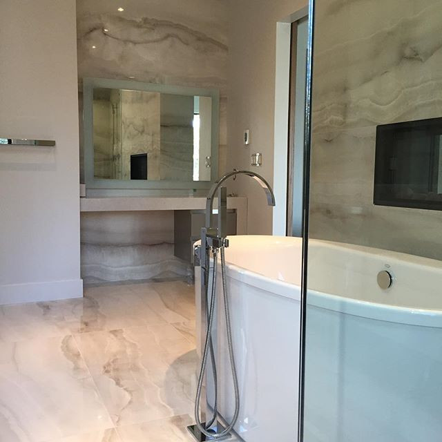 Inspiration for a large contemporary master bathroom in Orange County with flat-panel cabinets, grey cabinets, a freestanding tub, a corner shower, a two-piece toilet, gray tile, white tile, marble, grey walls, marble floors, an undermount sink, marble benchtops, grey floor and a hinged shower door.