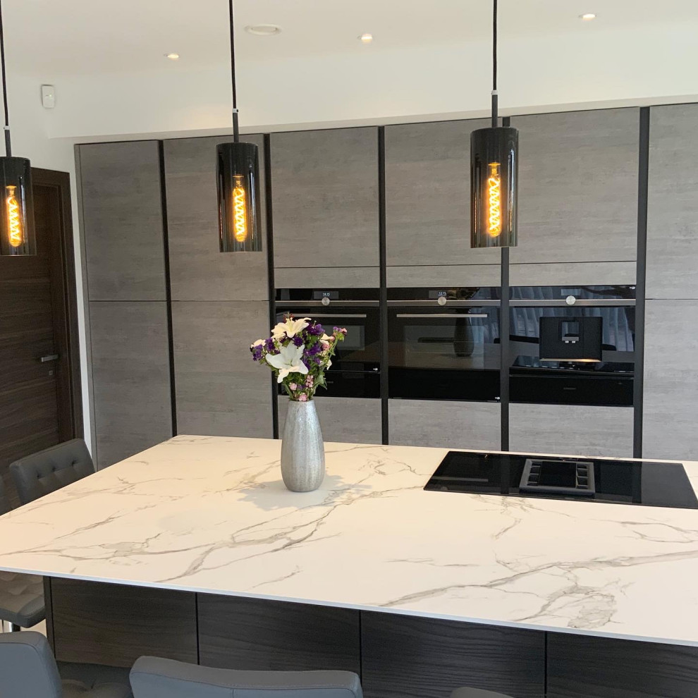 This is an example of a large contemporary l-shaped kitchen in Buckinghamshire with flat-panel cabinets, grey cabinets, with island and white benchtop.