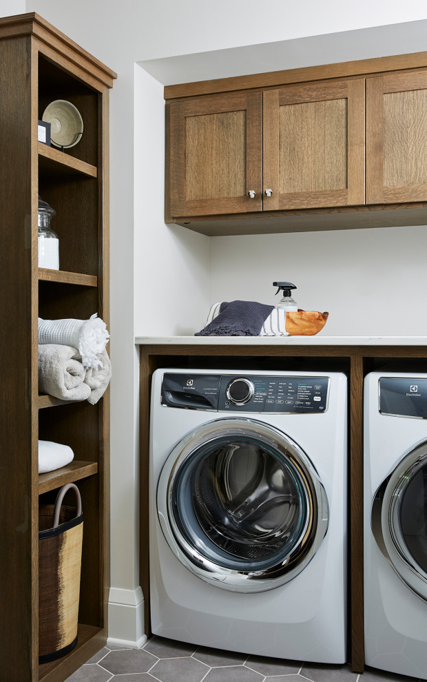 Mid-sized transitional laundry room in Minneapolis with recessed-panel cabinets, porcelain floors, a side-by-side washer and dryer, grey floor and white benchtop.
