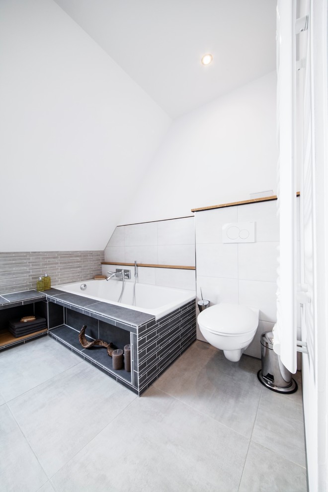 Photo of a small contemporary 3/4 bathroom in Other with a vessel sink, a drop-in tub, a curbless shower, a two-piece toilet, gray tile, ceramic tile, white walls and ceramic floors.