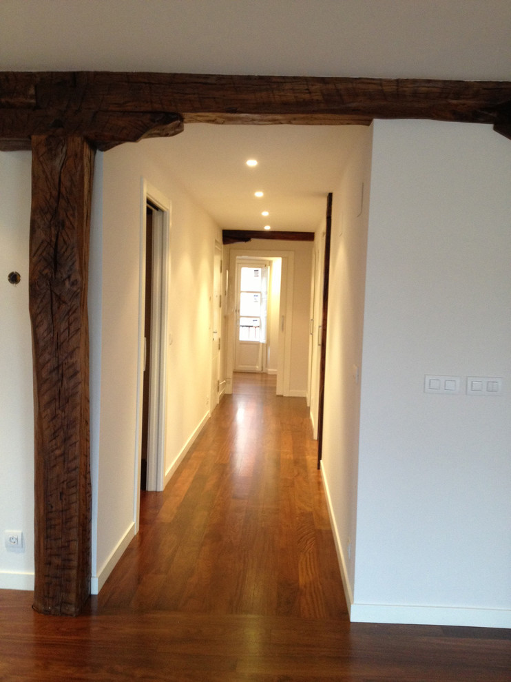 Design ideas for a mid-sized country hallway in Bilbao with white walls and dark hardwood floors.