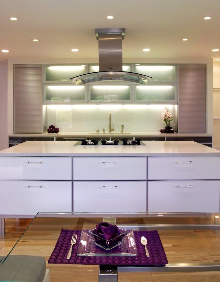 Photo of a mid-sized contemporary l-shaped open plan kitchen in San Francisco with an undermount sink, flat-panel cabinets, black cabinets, quartz benchtops, white splashback, stainless steel appliances, light hardwood floors, with island and brown floor.